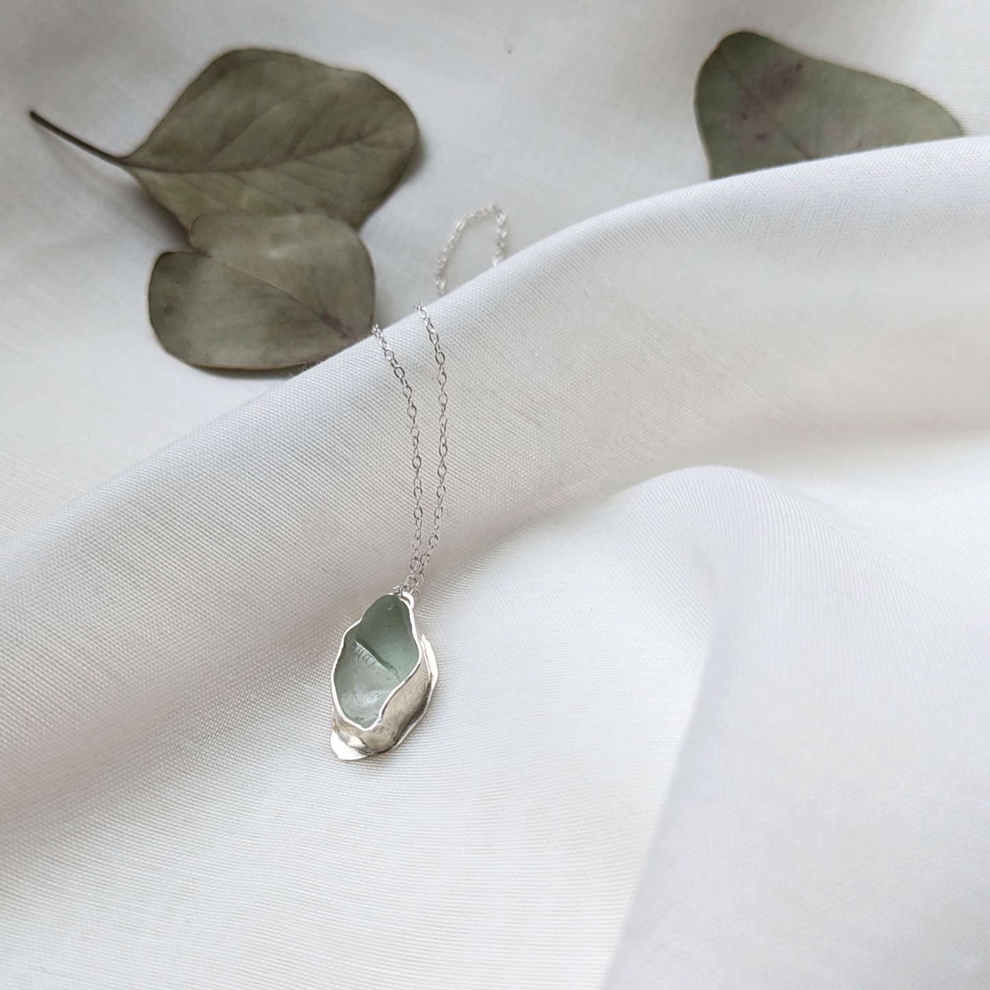 Turquoise sea glass necklace on white silk with eucalyptus leaves