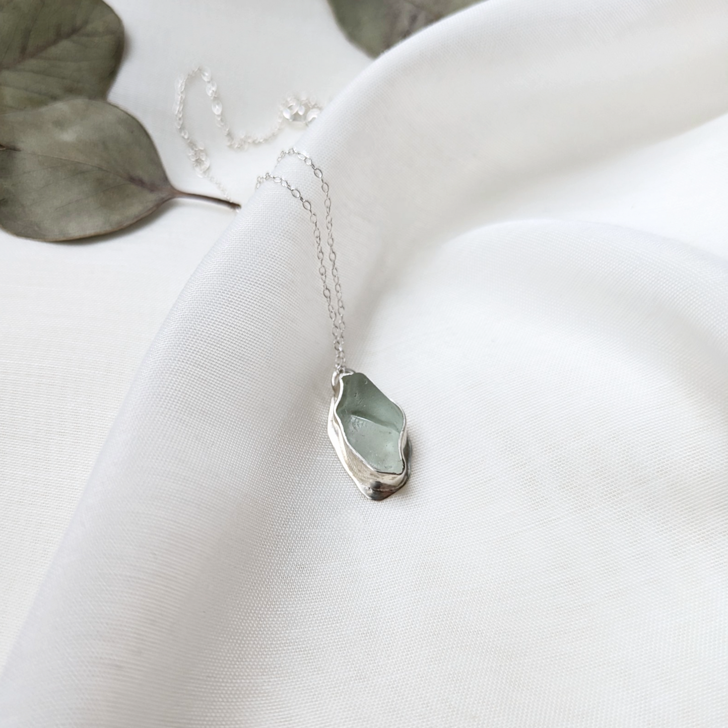 Turquoise sea glass necklace on white silk with eucalyptus leaves