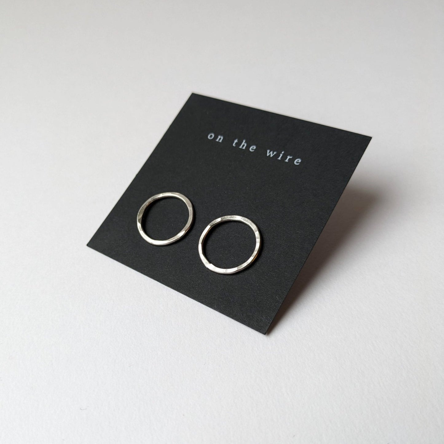 Big silver circle studs on black branded earring card
