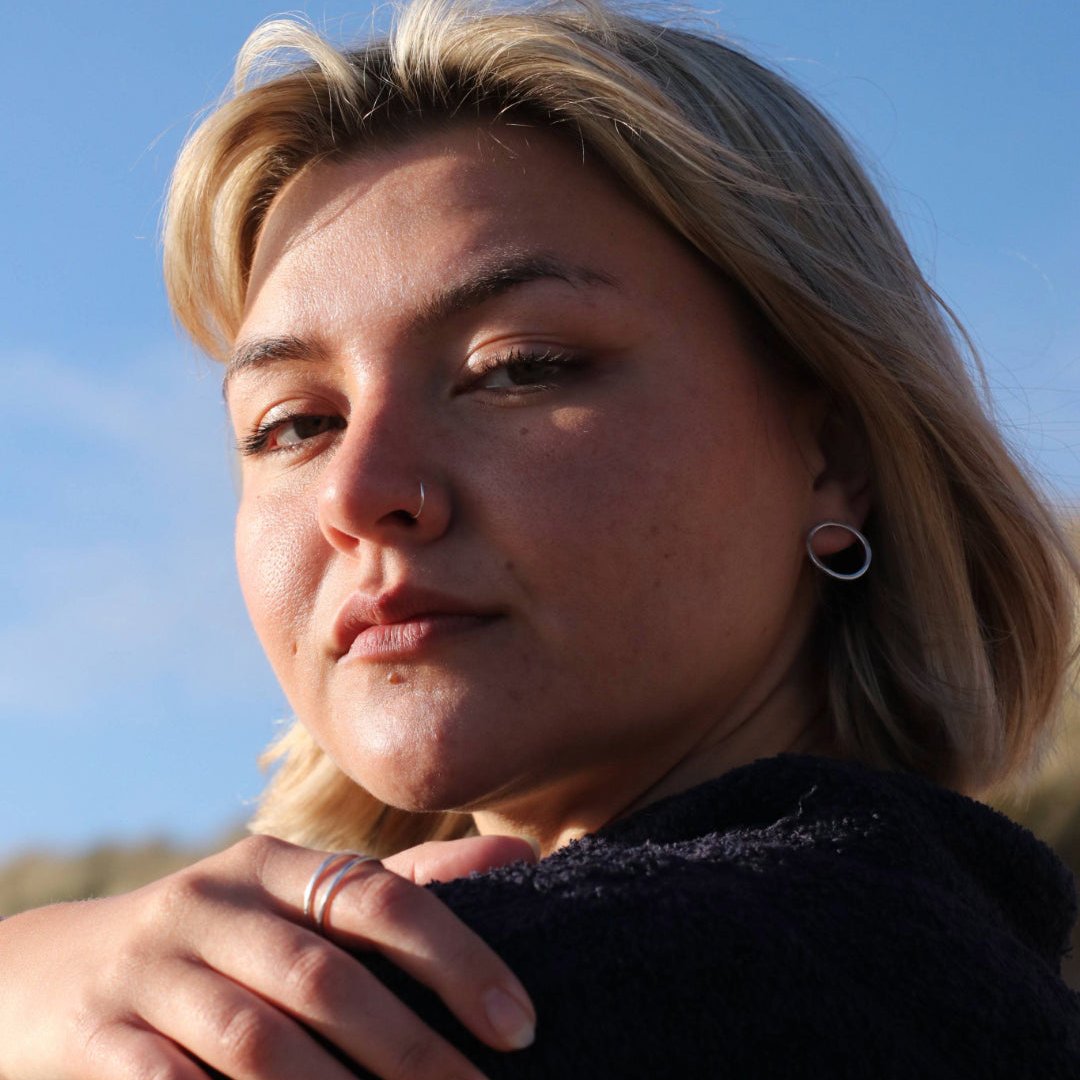 Woman wearing big silver circle studs with blue sky in background