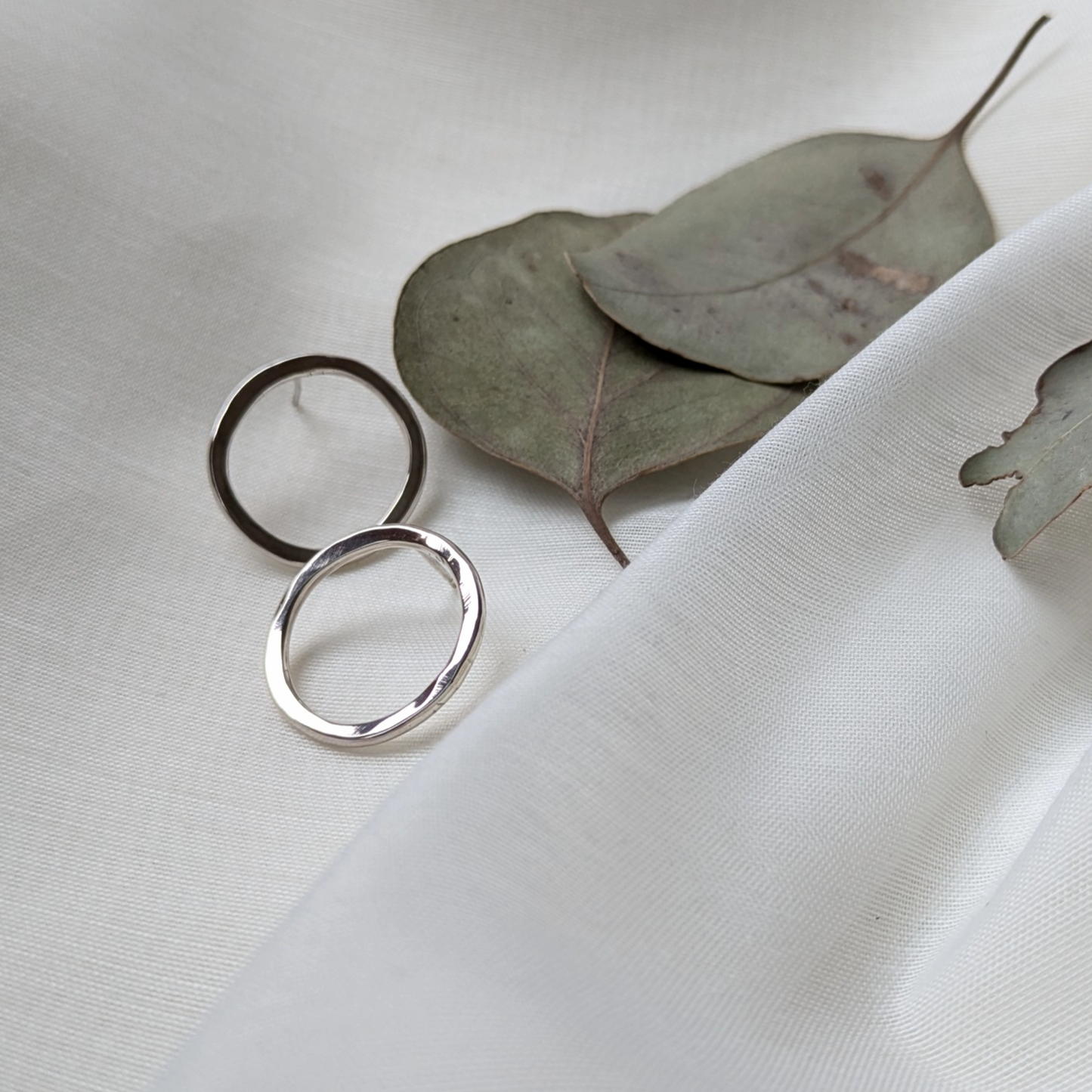 Big silver circle studs and eucalyptus leaves on white silk