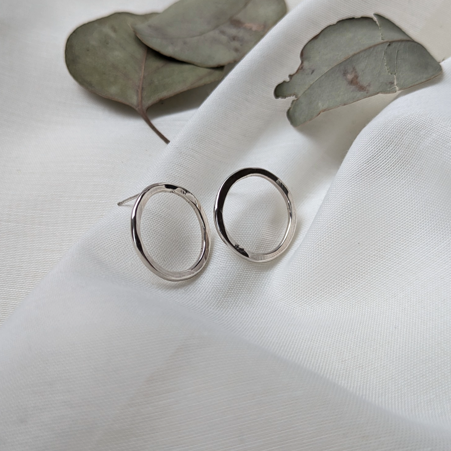 Big silver circle studs and eucalyptus leaves on white silk