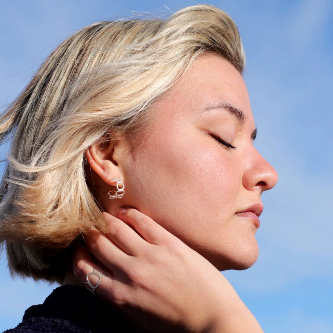 Silver pebble stack hoops on woman with sky in background