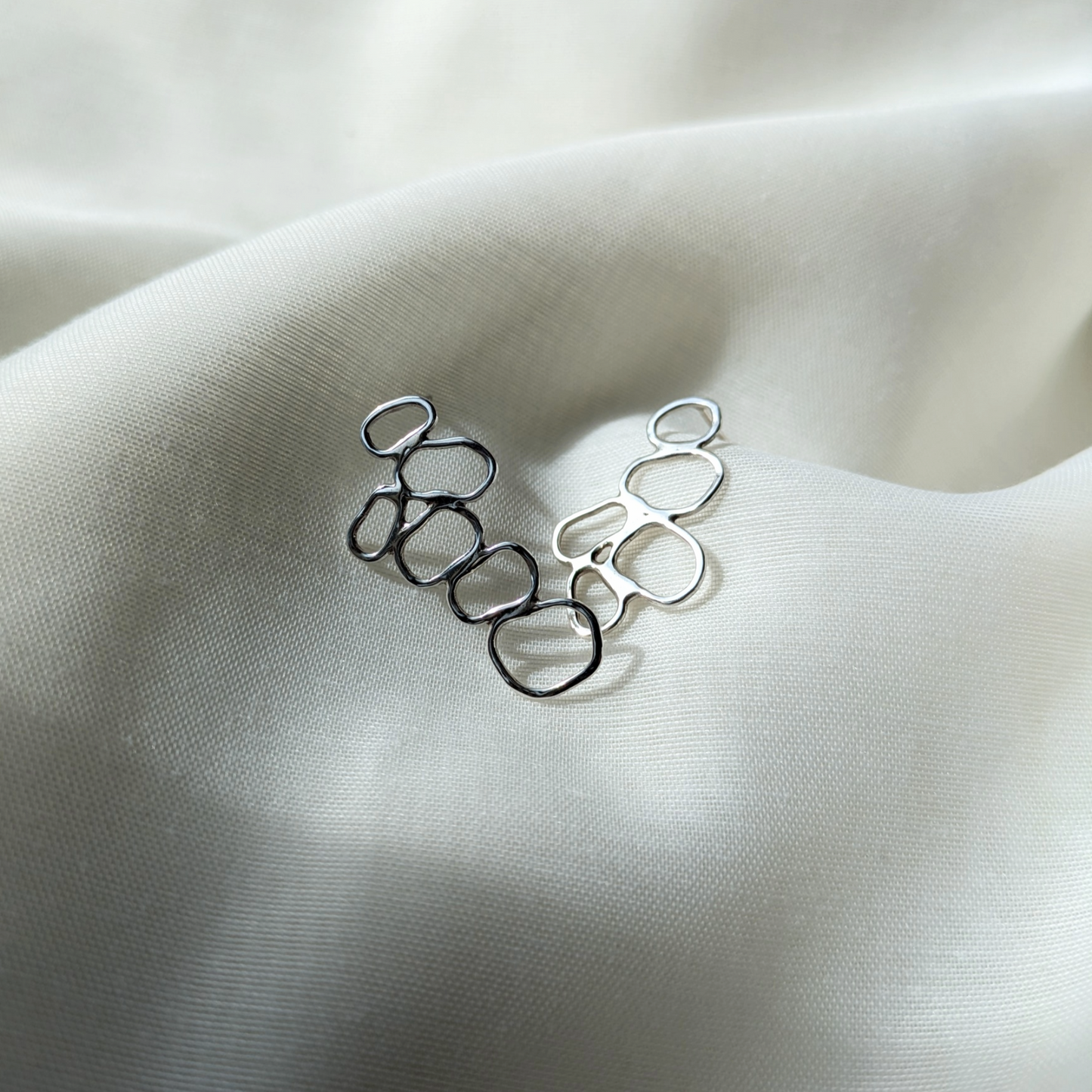 Silver pebble cluster earrings on white silk