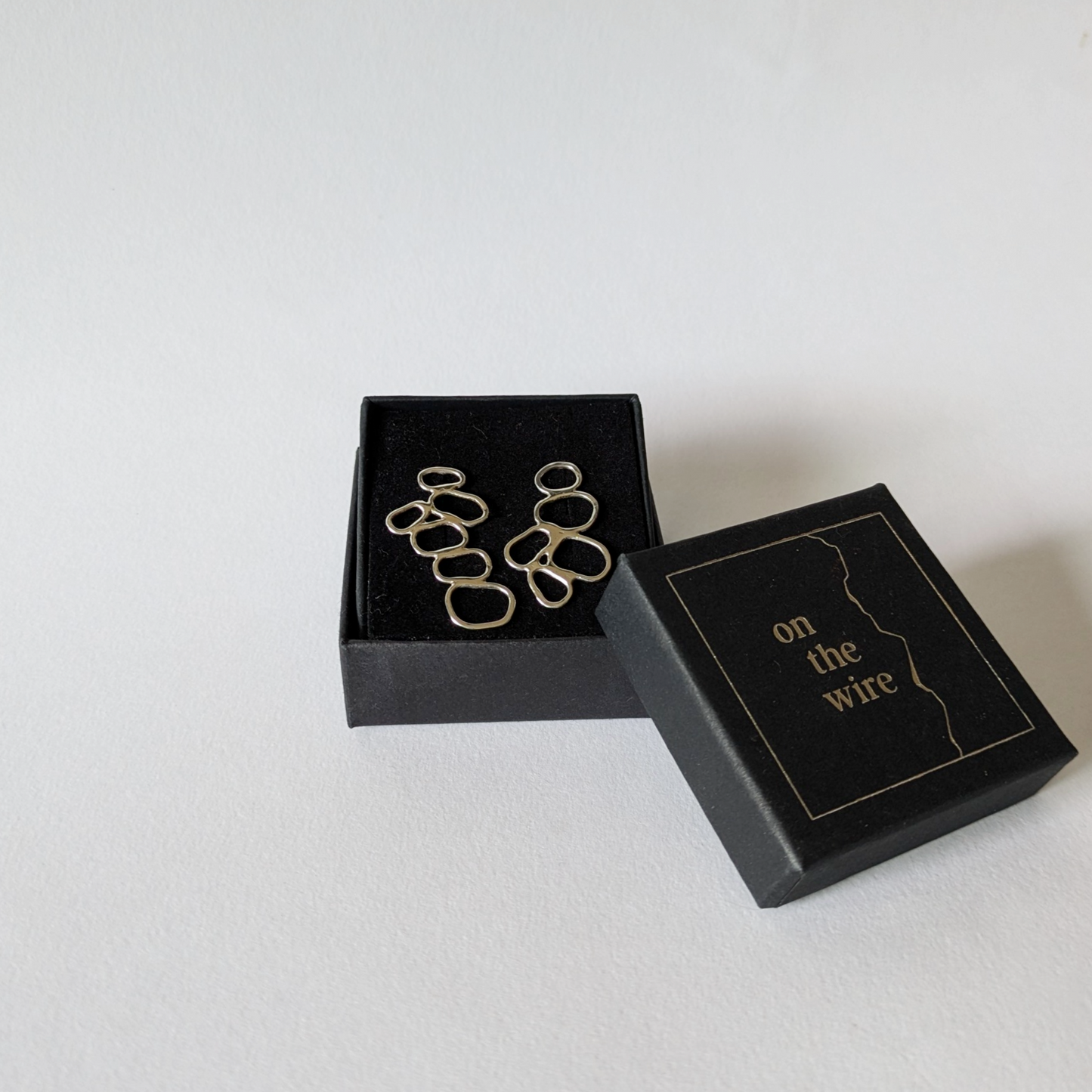 Silver pebble stack earrings in branded gift box on white background