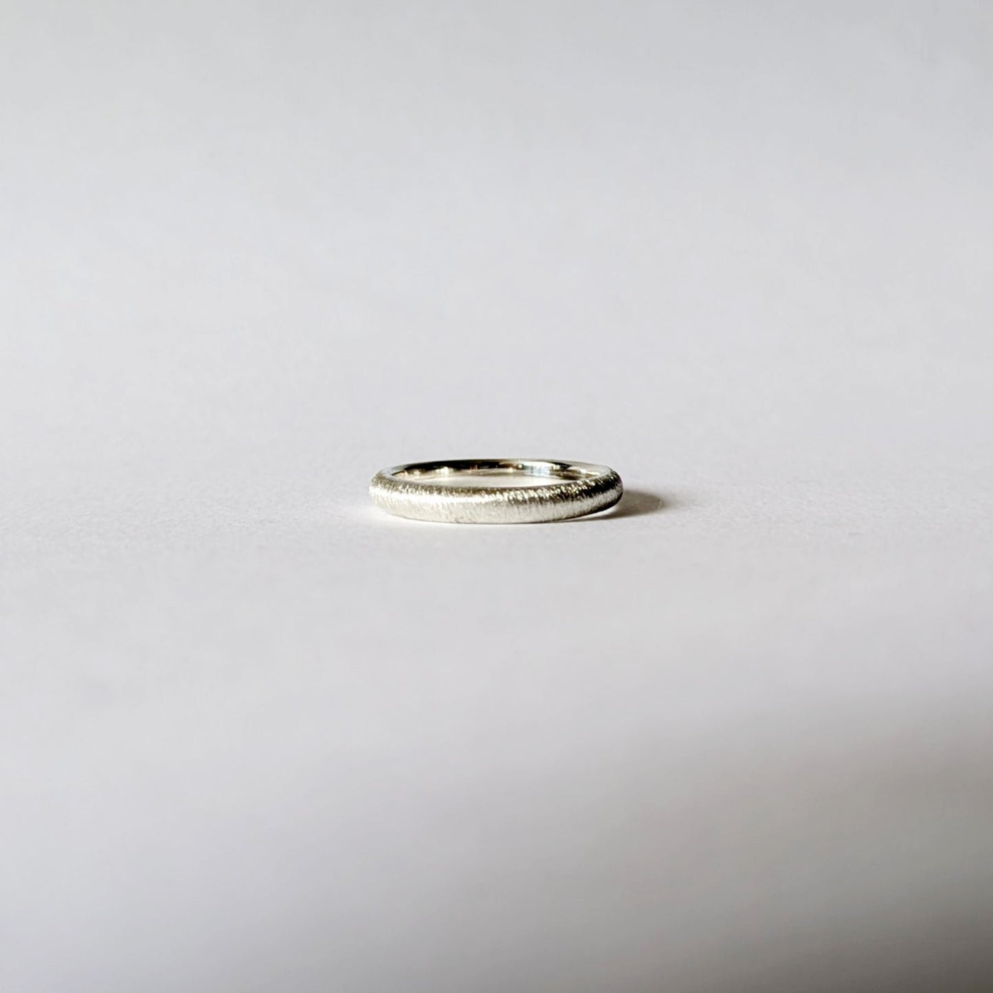 Line-textured thin d-shape ring with polished interior on white background