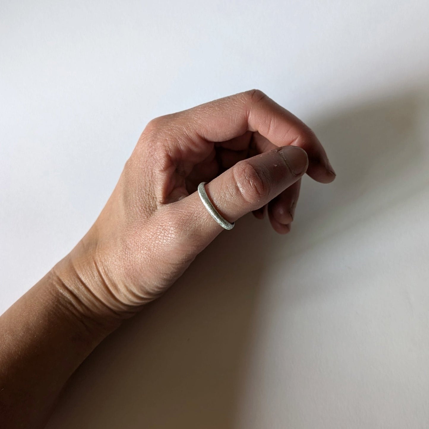 Textured d-shape ring on thumb of hand