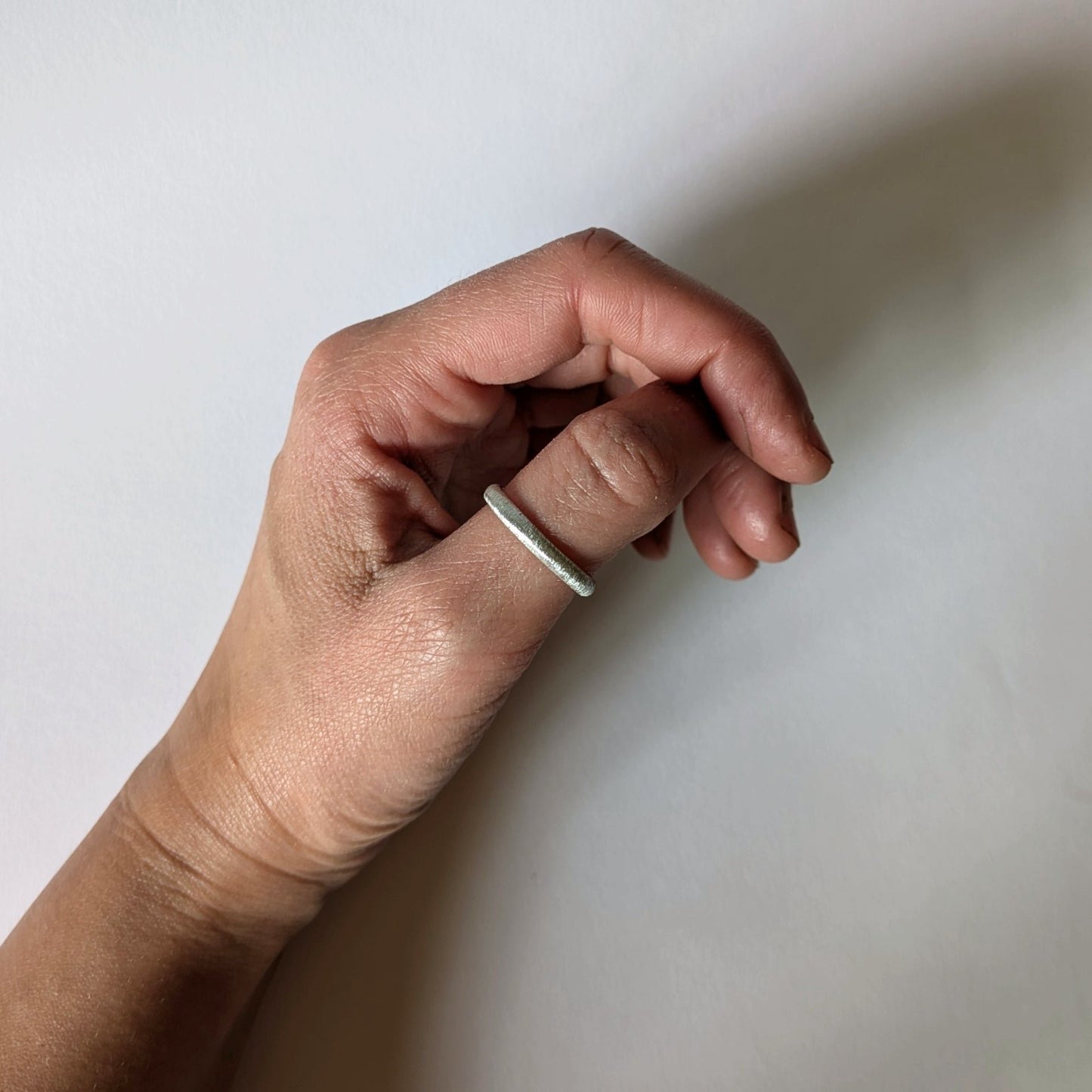 Textured d-shape ring on thumb of hand
