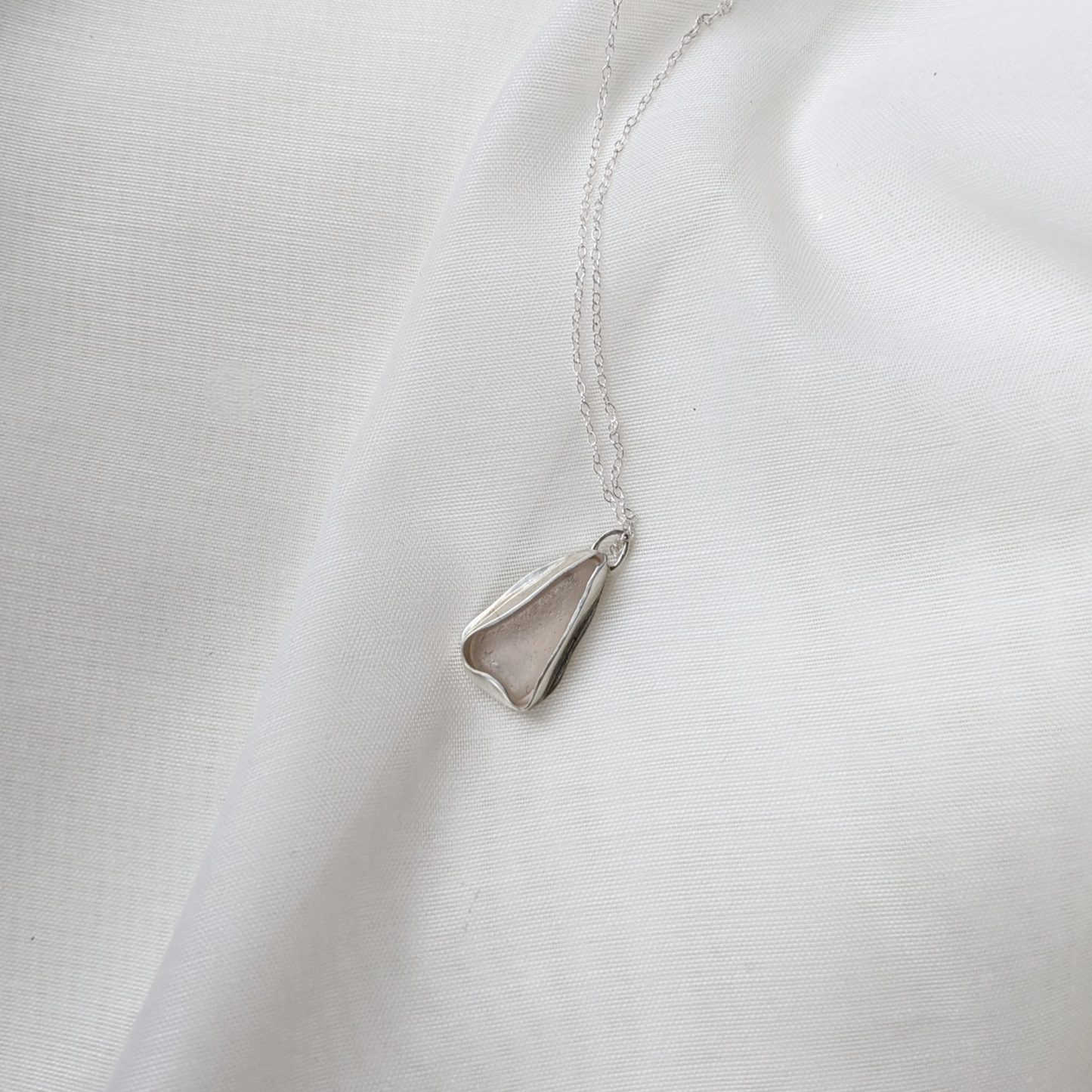 White sea glass necklace on silk background