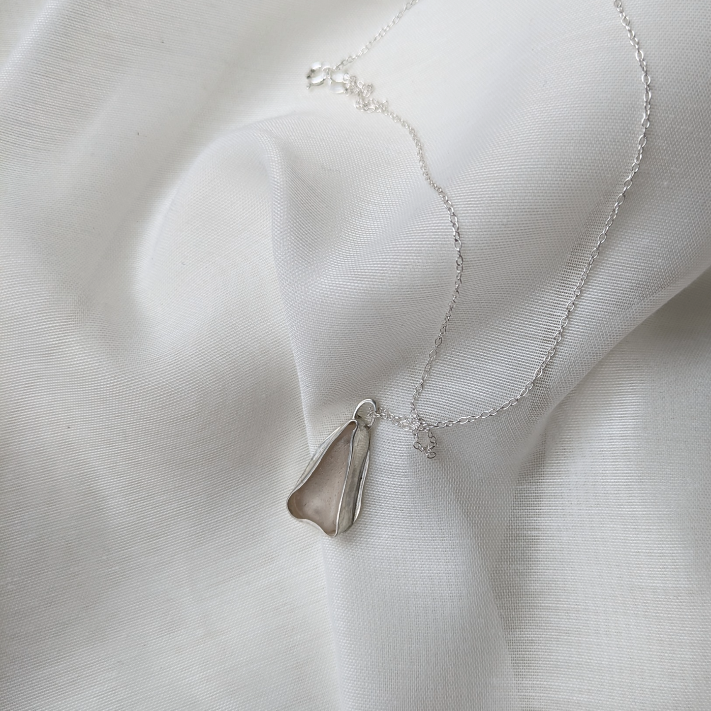 White sea glass necklace on silk background