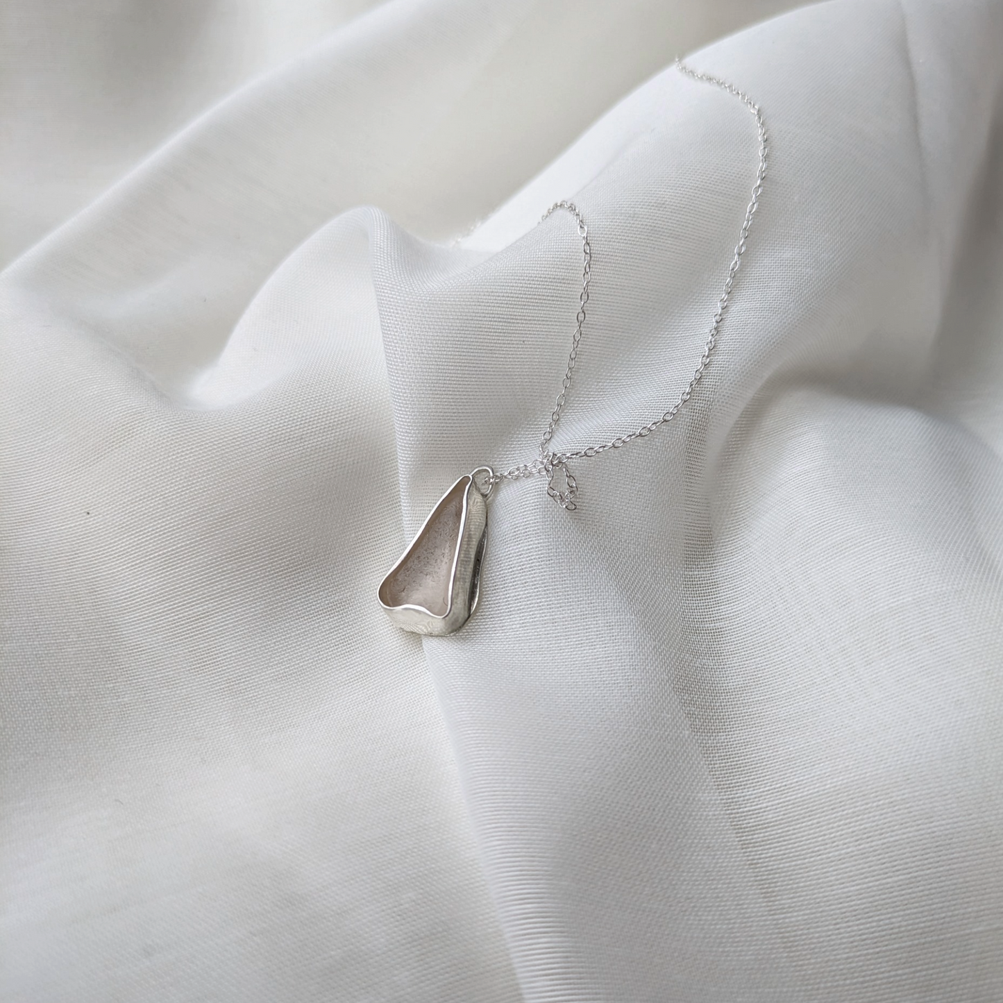 White sea glass necklace on silk background