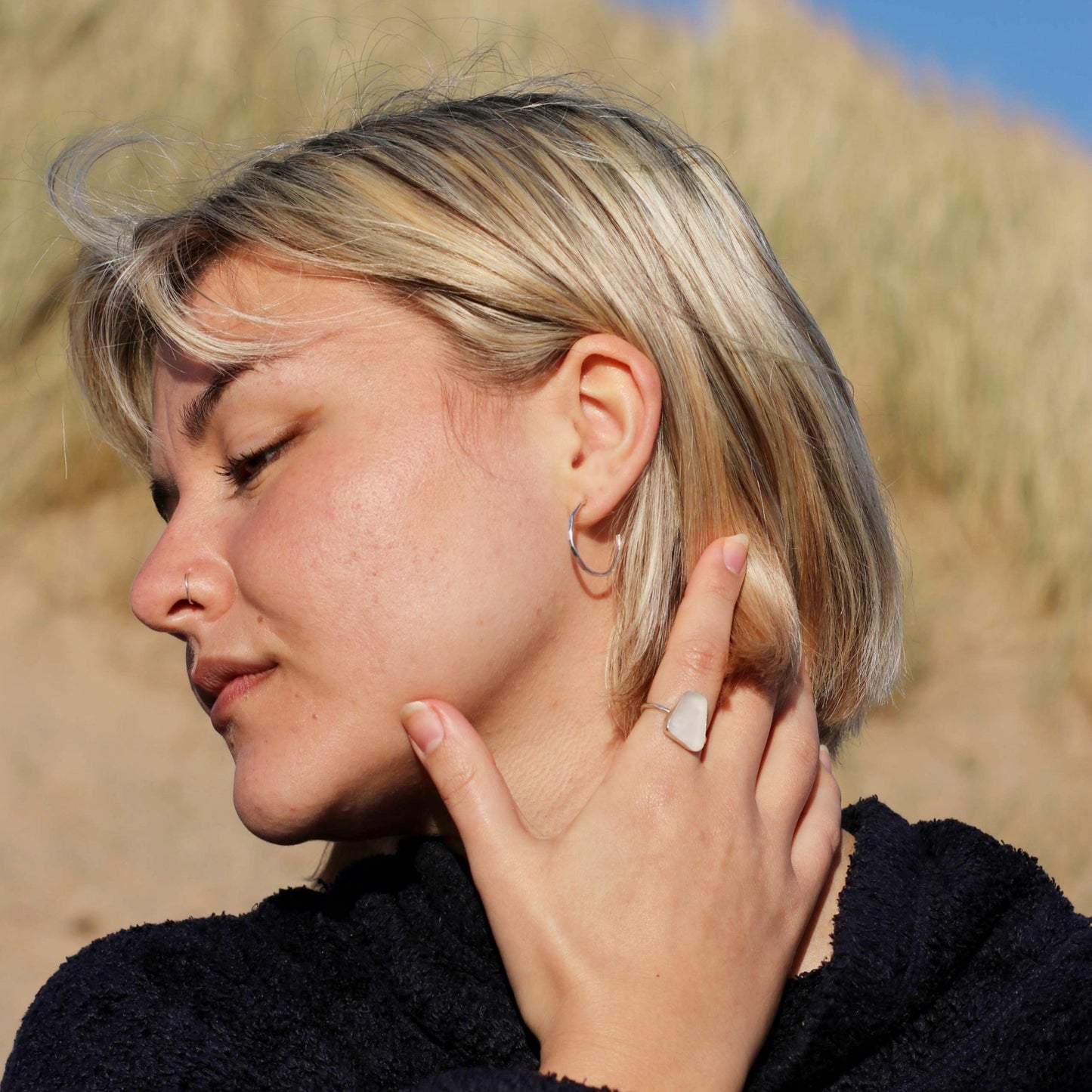 Woman wearing medium hammered hoops and a white sea glass ring on the beach