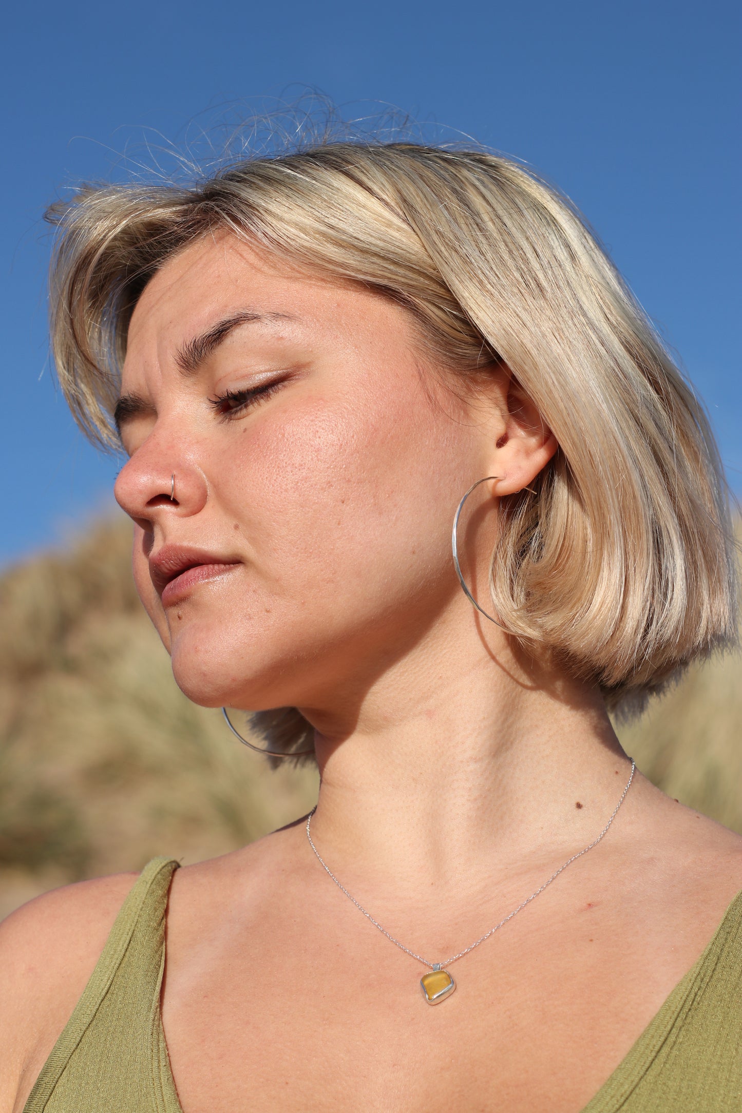 Woman wearing extra large hammered hoops on the beach