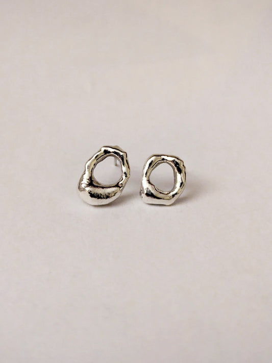 Pair of silver mini molten earrings on a light beige background