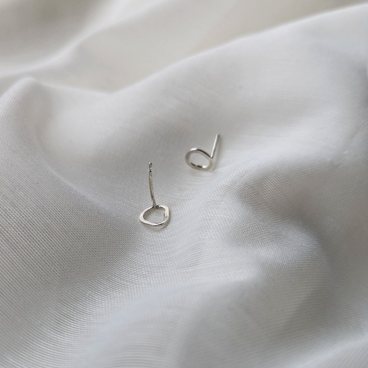 Silver pebble stud earrings on white silk