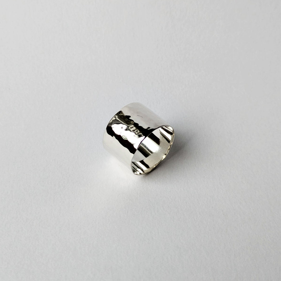 Hammered wide silver ring with polished interior on white background