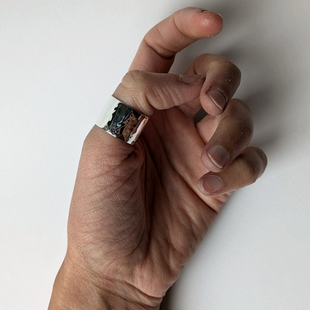 Hammered wide silver ring on thumb