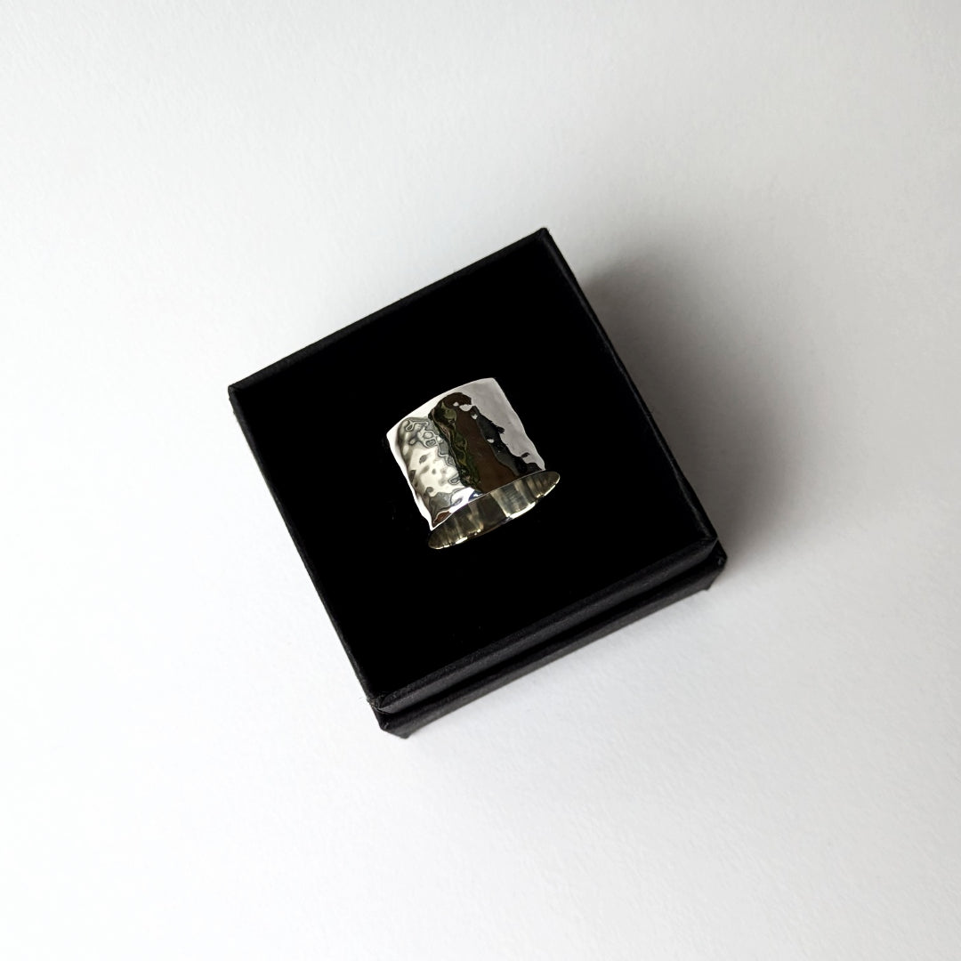Hammered wide silver ring in black gift box on white background