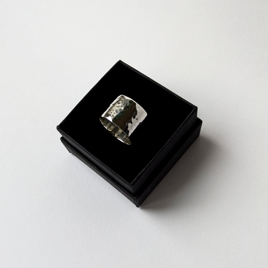 Hammered wide silver ring in black gift box on white background