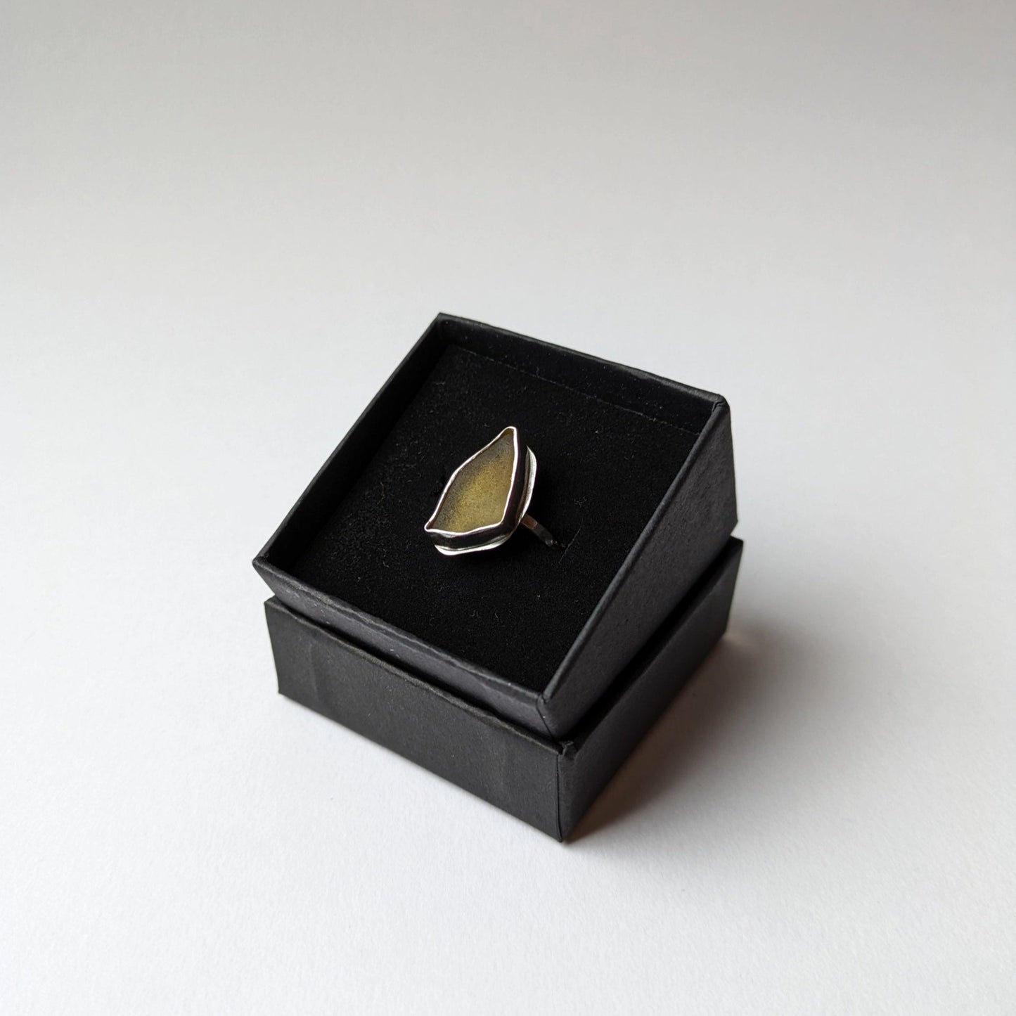 Green sea glass on a silver ring in a black gift box