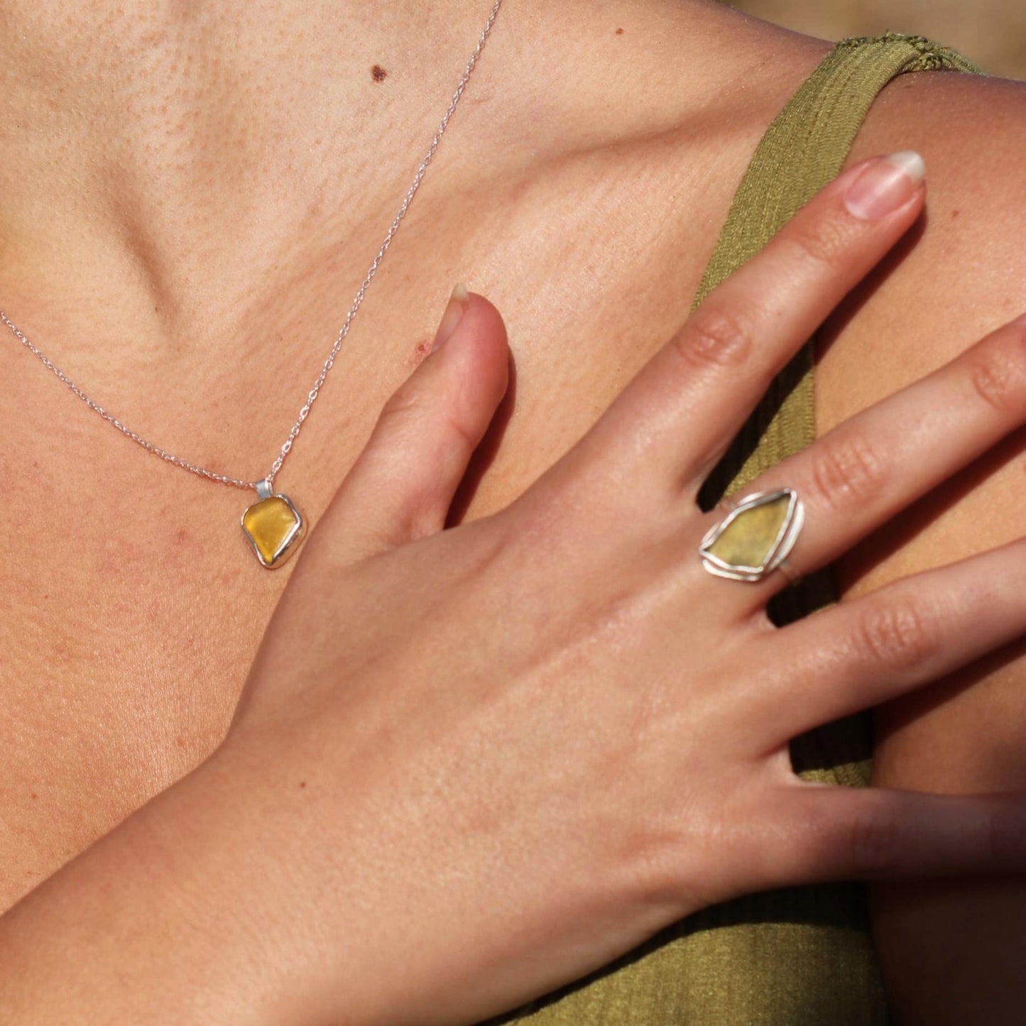 Woman wearing green sea glass silver ring and matching yellow sea glass necklace pendant