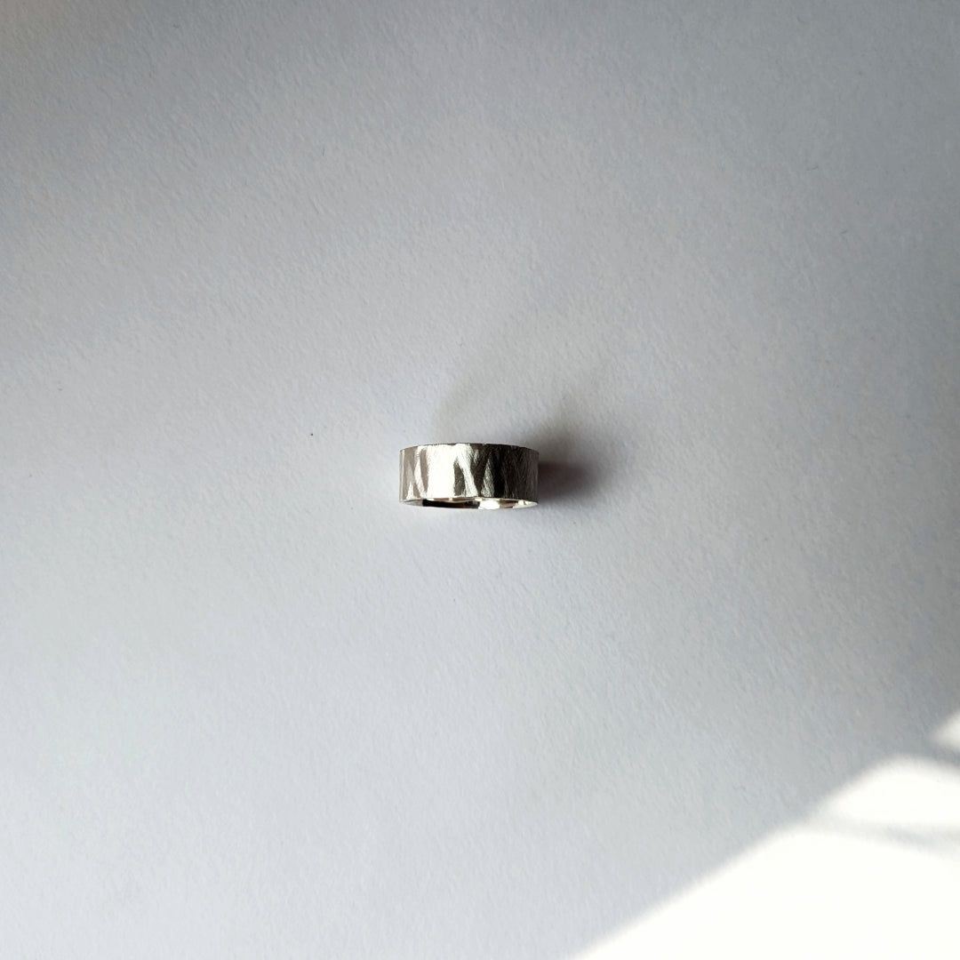 Small feather textured silver ring on white background