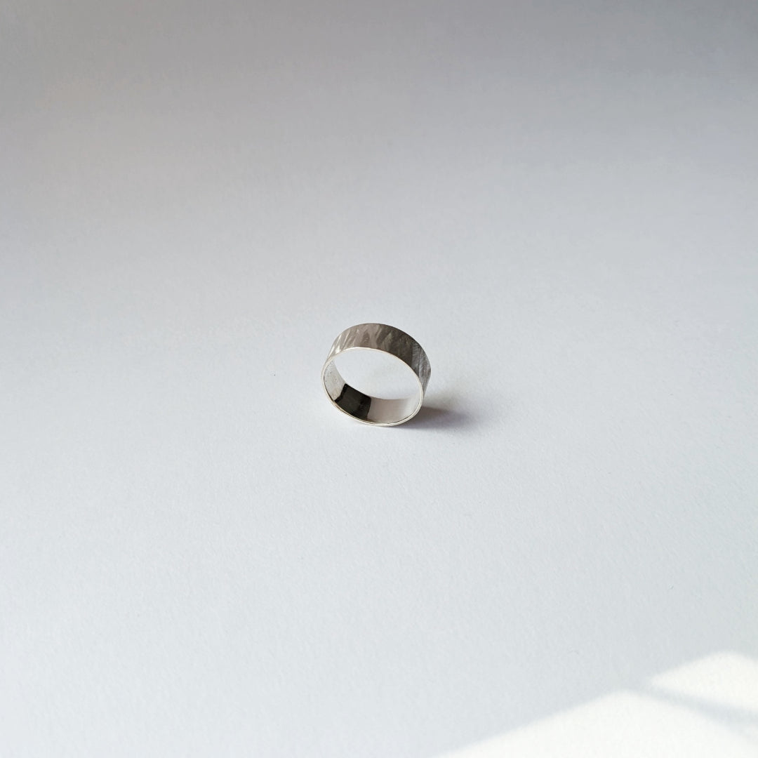 Small feather textured silver ring on white background