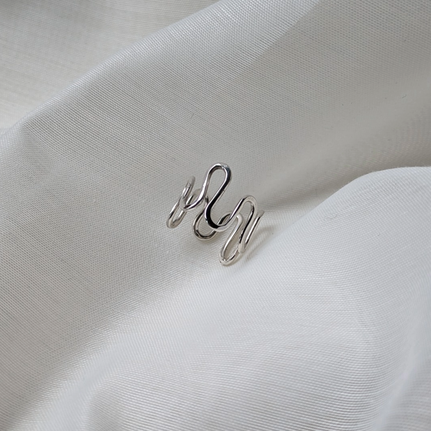 Silver wiggle ring on white silk