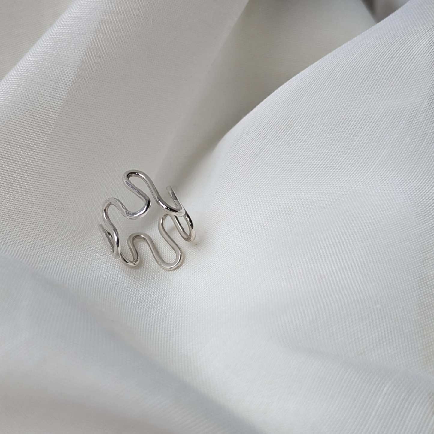 Silver wiggle ring on white silk