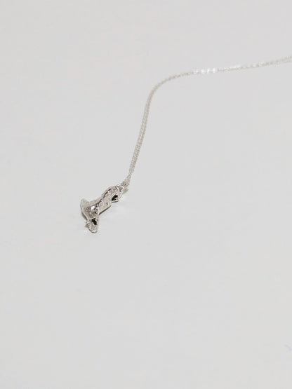 A silver pendant embedded green sea glass shards lying on a white background