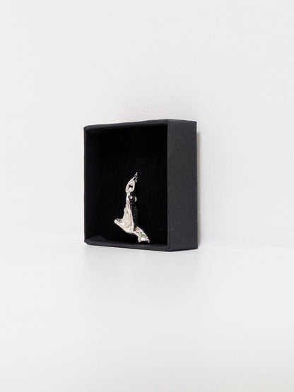 Side angle of a silver pendant embedded green sea glass shards in a black jewellery box on a white background