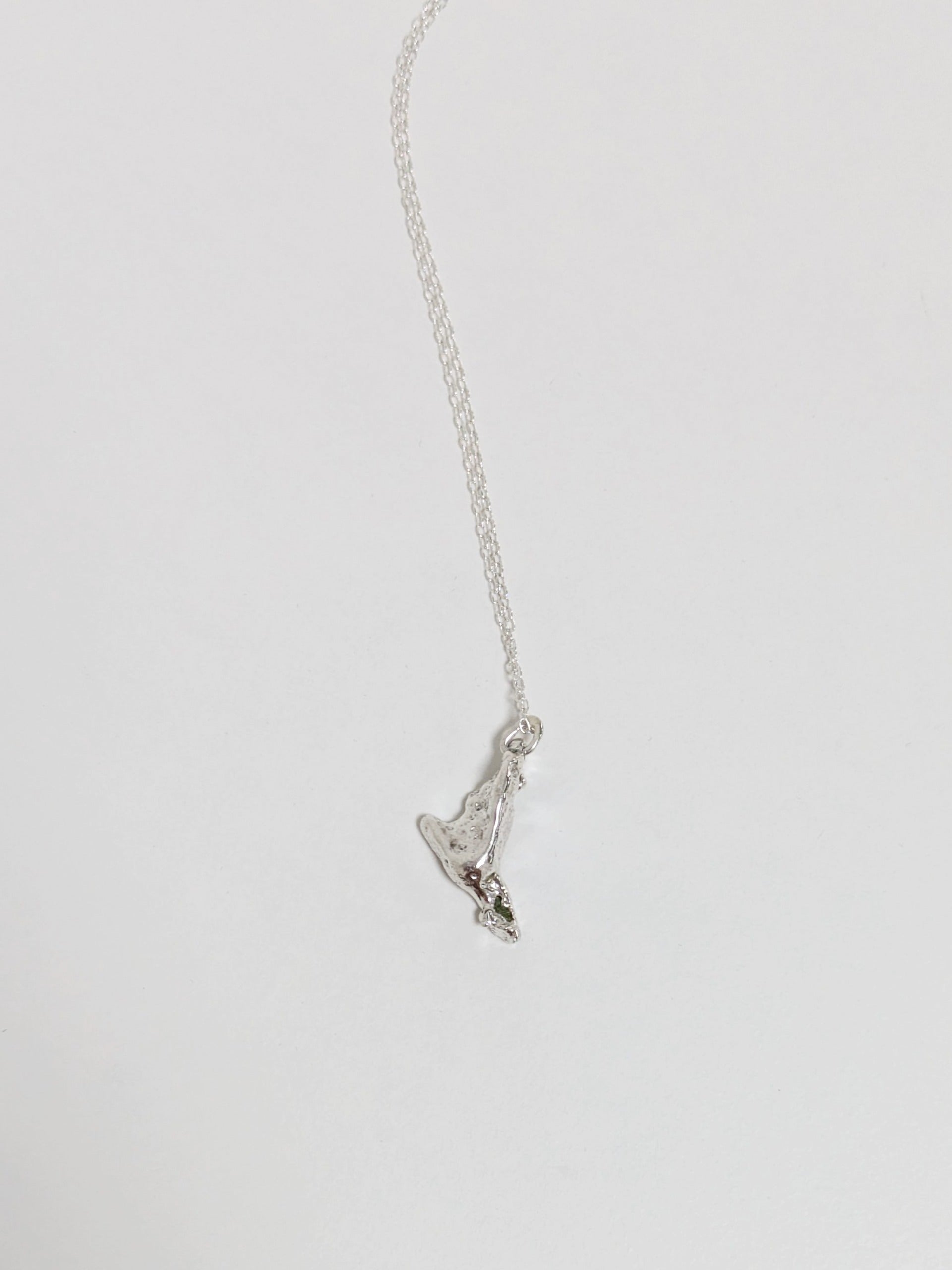 Close up of a silver pendant embedded with green sea glass shards on a white background