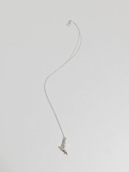 A silver pendant embedded with green sea glass shards on a silver chain lying on a white background