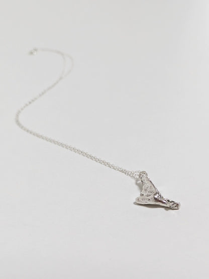 A silver pendant embedded green sea glass shards lying on a white background