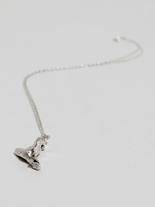 Silver necklace with embedded green sea glass shards on a light gray background