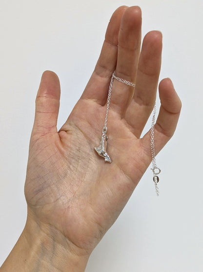 Hand holding a silver pendant embedded green sea glass shards with a white background