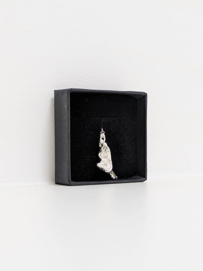 Side angle of a silver pendant embedded green sea glass shards in a black jewellery box on a white background