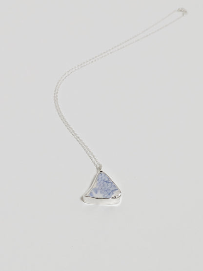 Necklace with a triangular blue floral sea pottery pendant on a light gray background