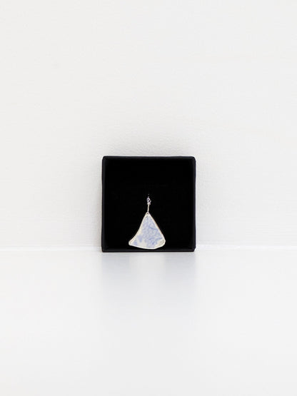 Black jewellery display box with a blue floral sea pottery pendant on a white background
