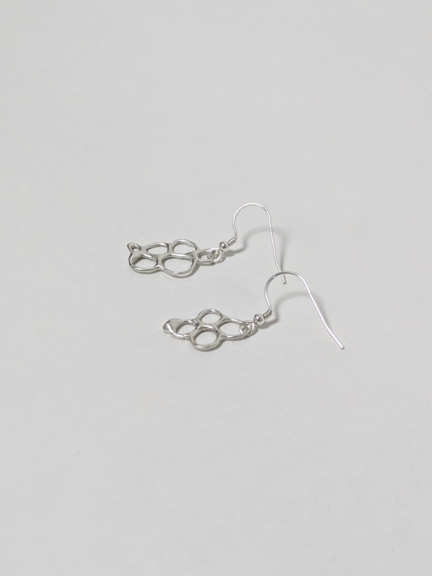 Organic shaped silver drop earrings on white background