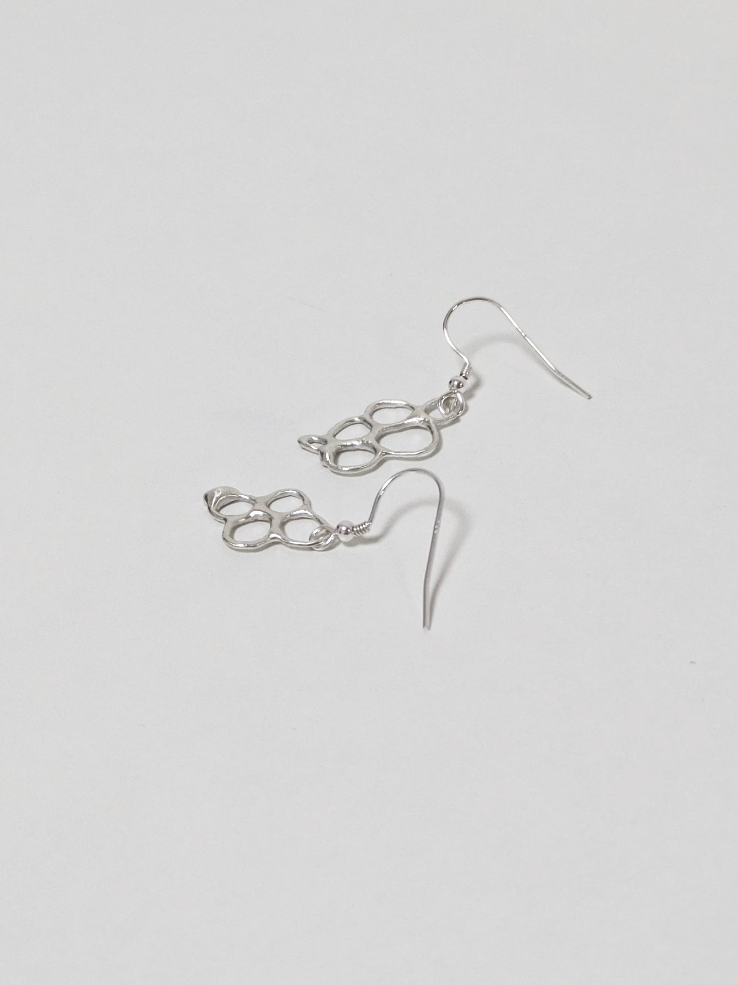 Organic shaped silver drop earrings on white background