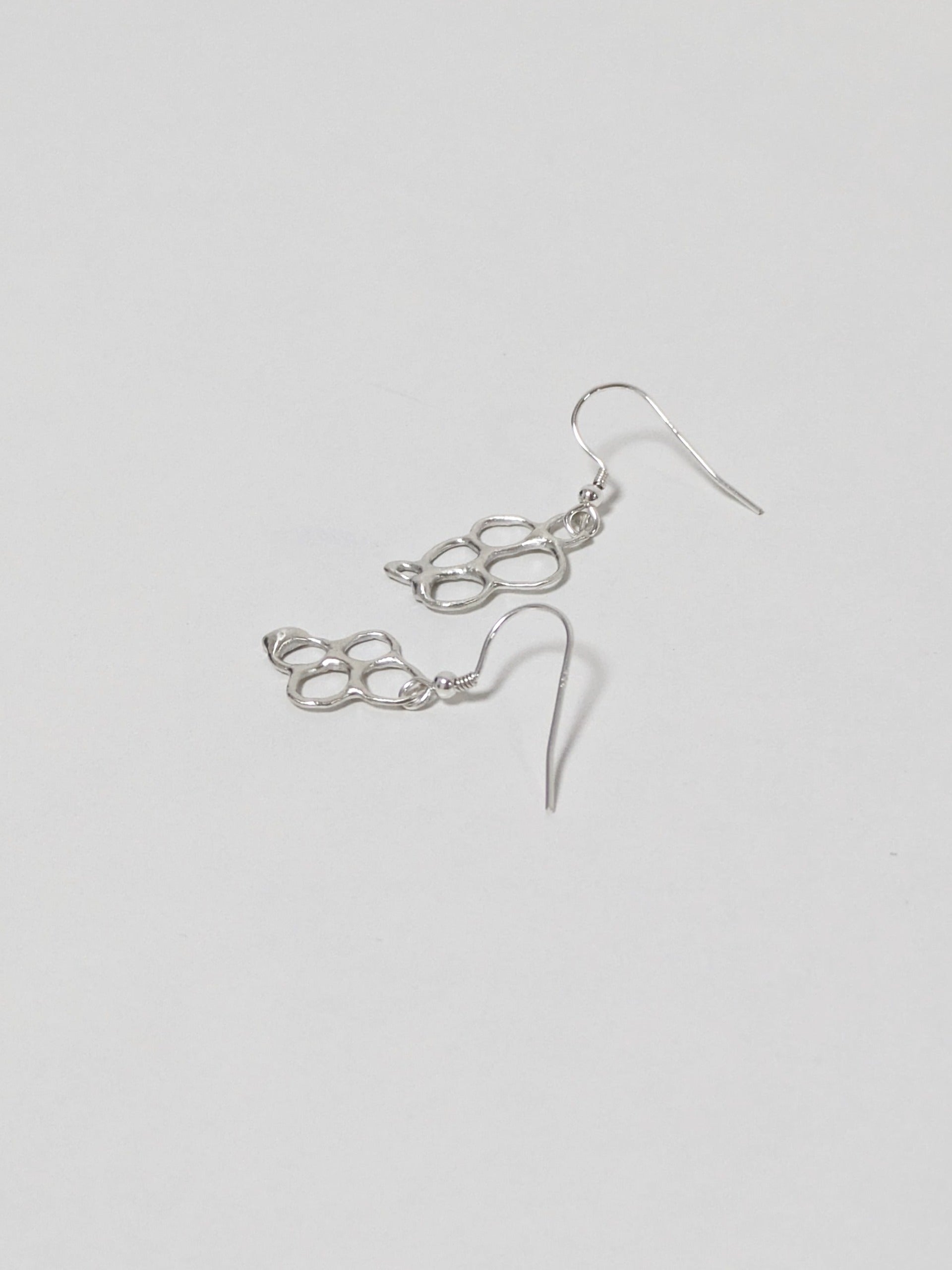 Organic shaped silver drop earrings on white background