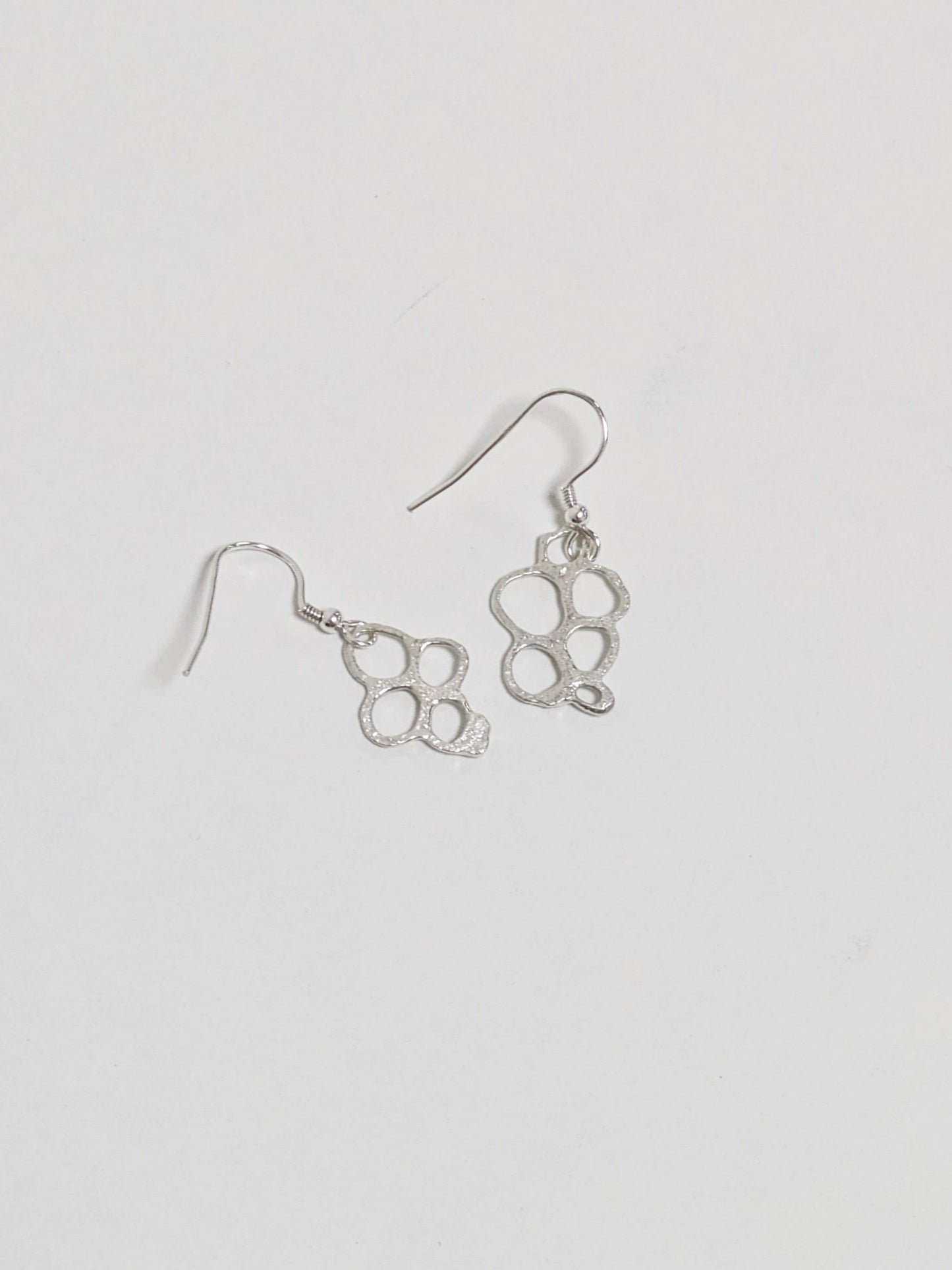 Back of organic shaped silver drop earrings on white background