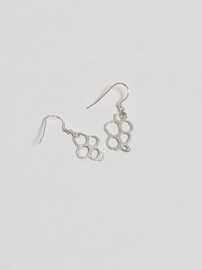 Back of organic shaped silver drop earrings on white background