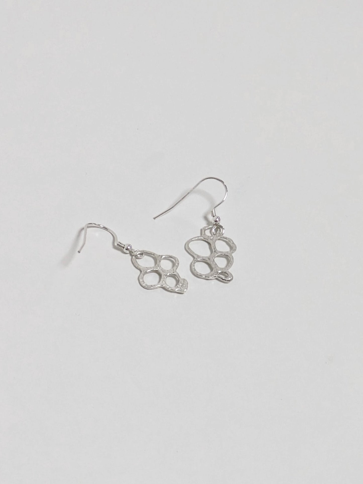 Back of organic shaped silver drop earrings on white background