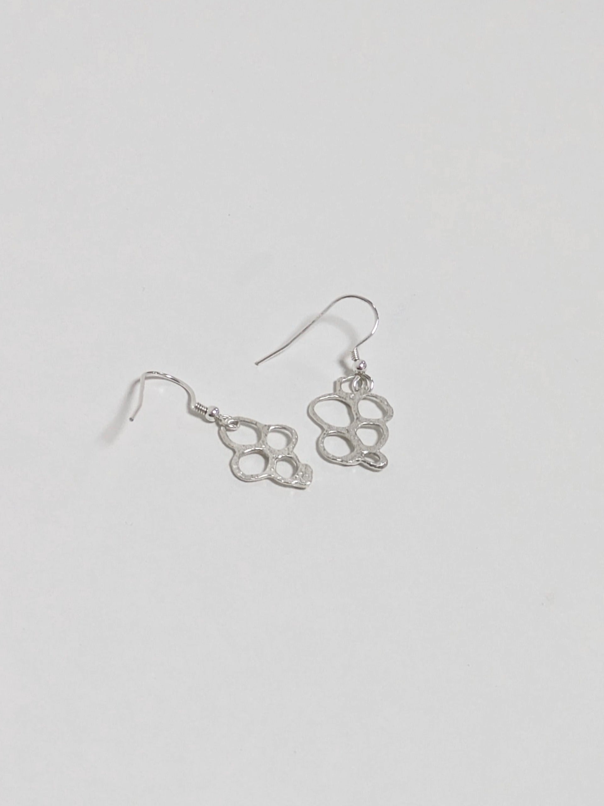 Back of organic shaped silver drop earrings on white background