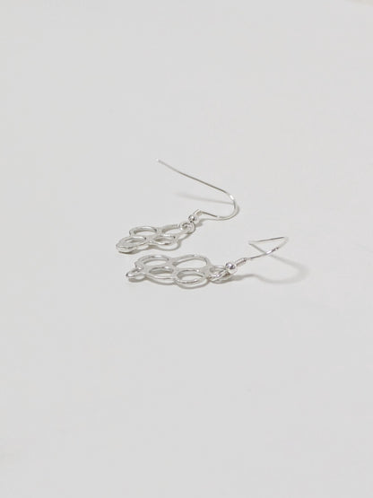 Side view of organic shaped silver drop earrings on white background