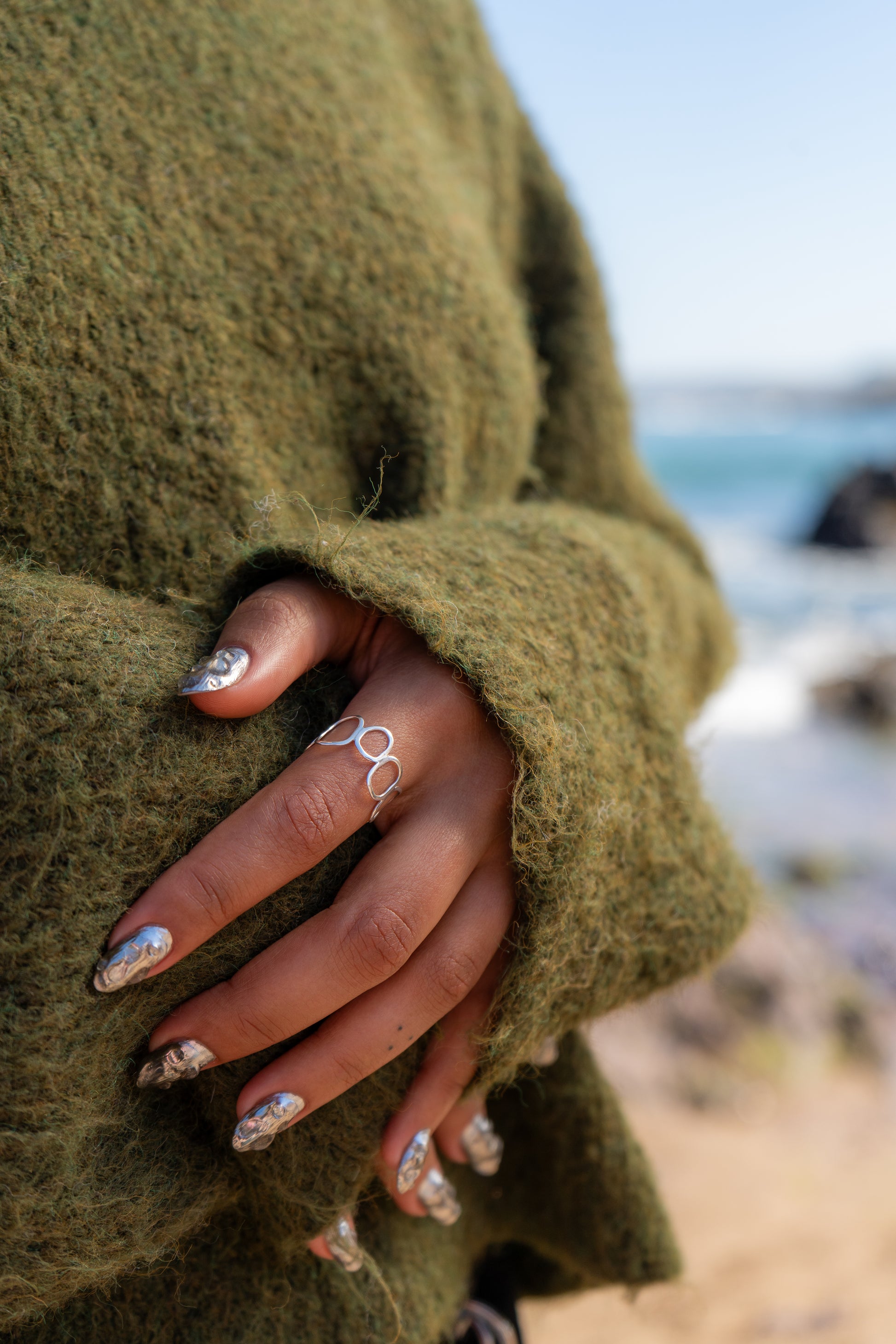 close up of woman wearing pebble shaped ring on the beach