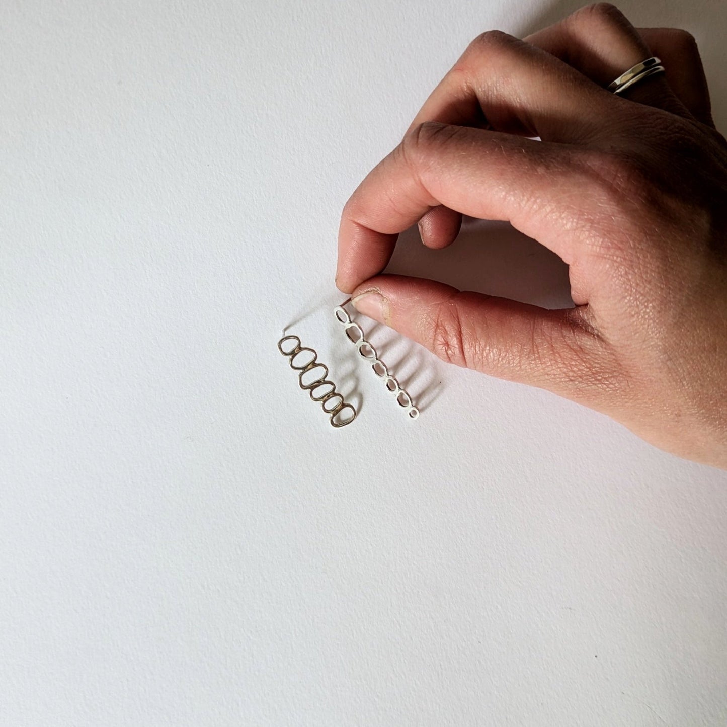 Hand holding Silver Stacked Cairn Studs on white background