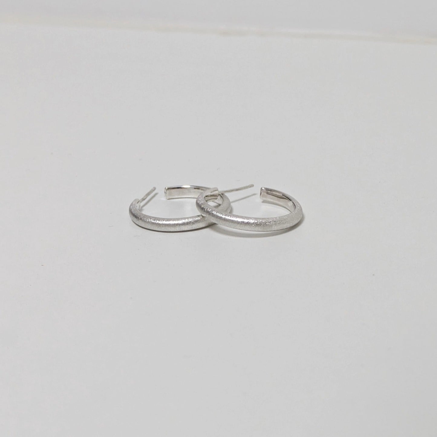 Two satin textured thin hoops on white background